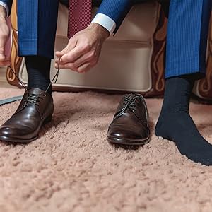 a man is wearing a pair of black socks and brown leather shoes