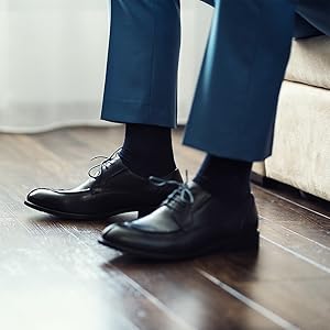 a men''s feet wearing a pair of black socks and leather shoes